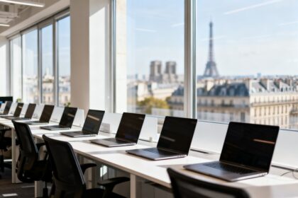 Open space lumineux d'une start-up technologique avec postes de travail et baies vitrees donnant sur une ville europeenne.