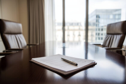 Salle de réunion d'entreprise avec deux fauteuils vides face à face et un contrat ouvert sur une table