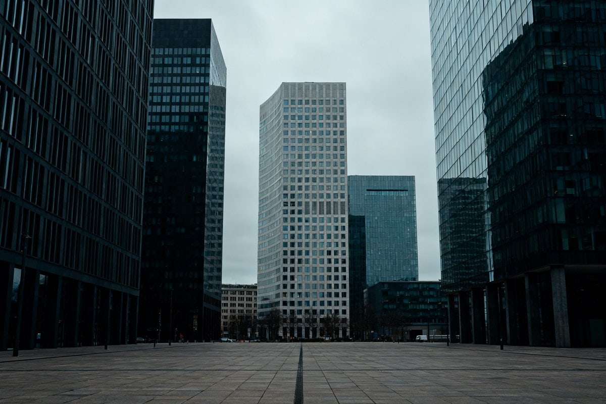 Quartier d'affaires europeen aux tours de bureaux sous un ciel gris, esplanade deserte.