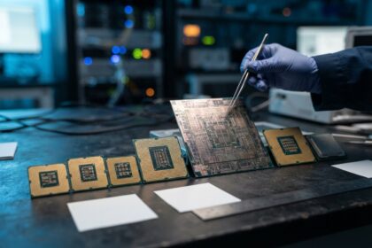 Plusieurs processeurs de tailles différentes alignés sur un établi, une main gantée saisissant une grande puce à la pince