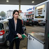 Une salariée en veste marine fait le plein de gazole d'une Renault Clio grise dans une station-service Carrefour