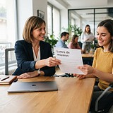 Une responsable RH tend une lettre de mission à une collègue en fauteuil roulant, assises à une table de bureau